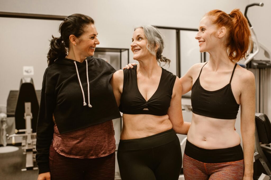 Three women enjoying fitness and friendship in a gym, embracing healthy living.