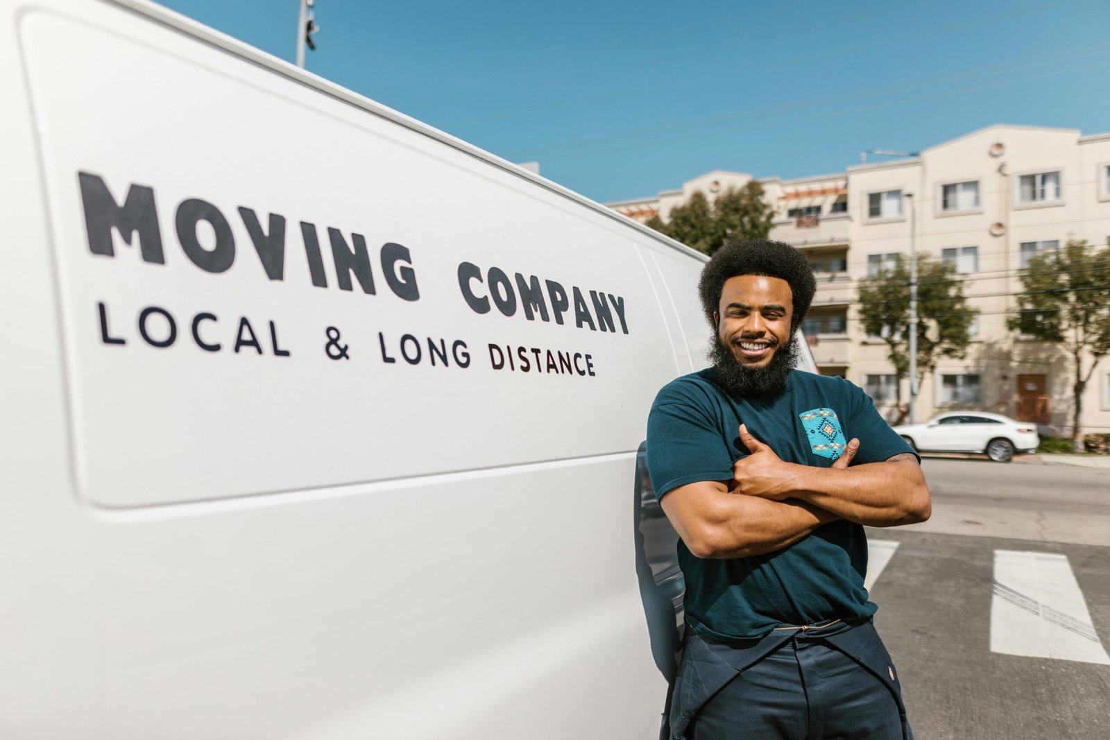 pexels-photo-7464643-7464643 A cheerful mover standing confidently beside a moving company's van, ready for local or long distance relocation services.